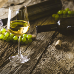 white wine on table with grapes and wine bottles